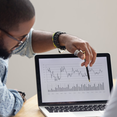 Man pointing to laptop with chart displaying.