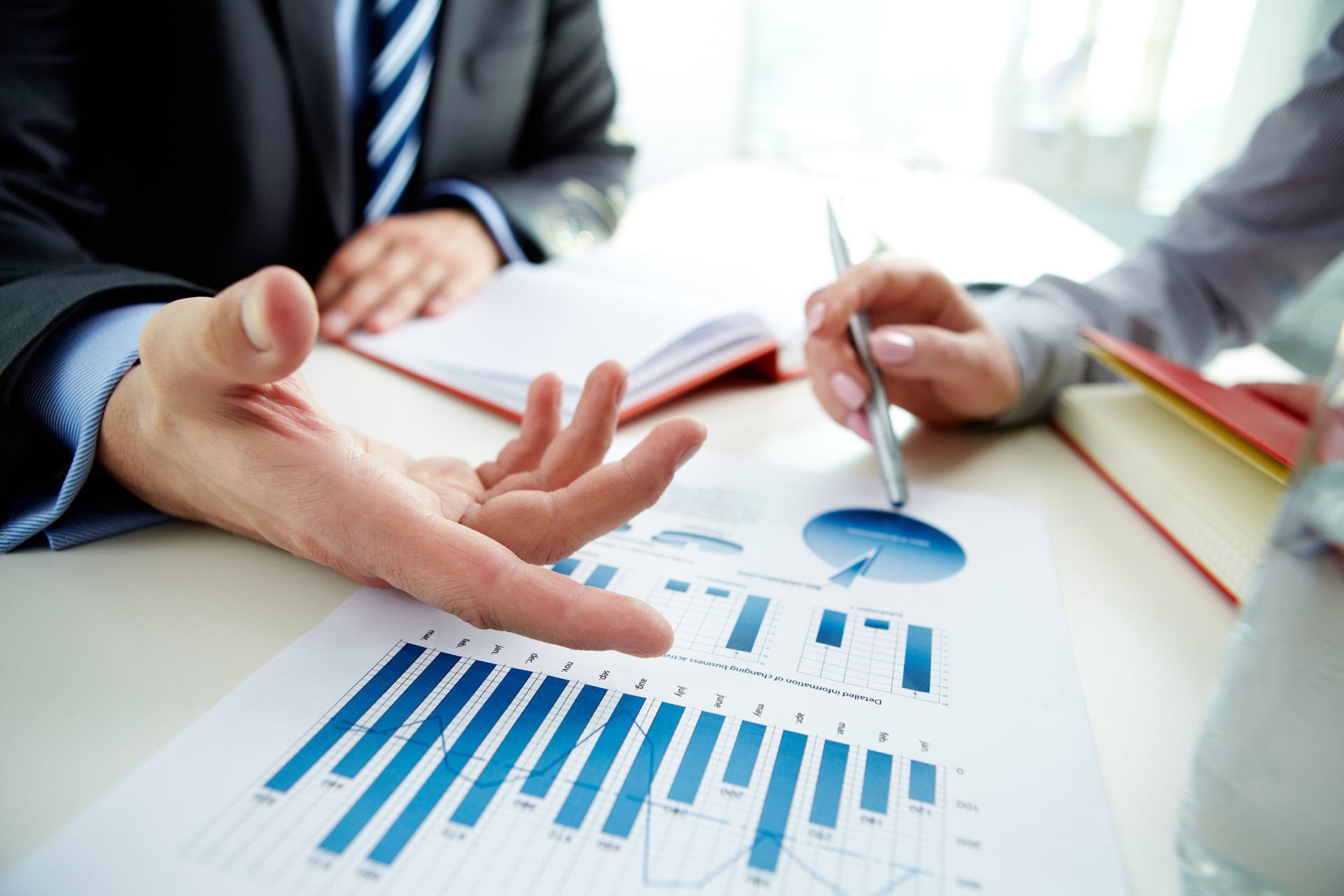 Hands pointing to a paper with graphs on it.